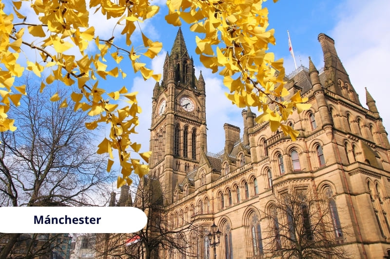 Ayuntamiento de Mánchester en otoño con torre del reloj gótica y hojas doradas