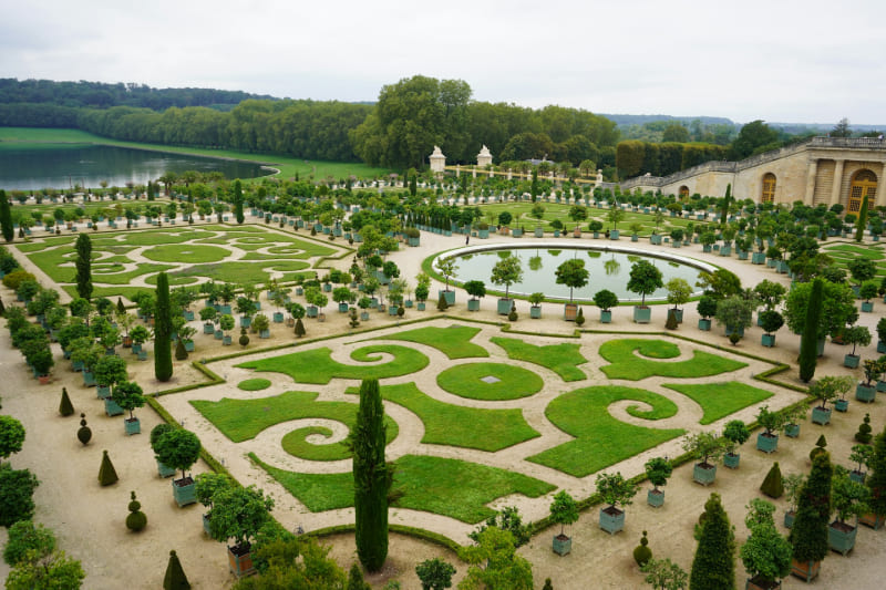 Jardines del Palacio de Versalles con parterres geométricos, estanques ornamentales y amplias zonas verdes en Francia.
