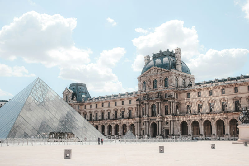 Vista de la pirámide de cristal del Museo del Louvre en París frente al histórico palacio que alberga el museo.