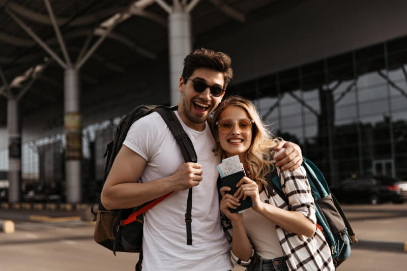 Pareja de turistas con mochilas y pasaportes en la terminal de un aeropuerto antes de un vuelo.